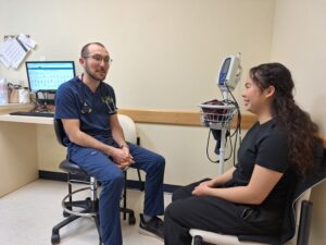 Primary care provider discusses with relaxed patient in an examination room.